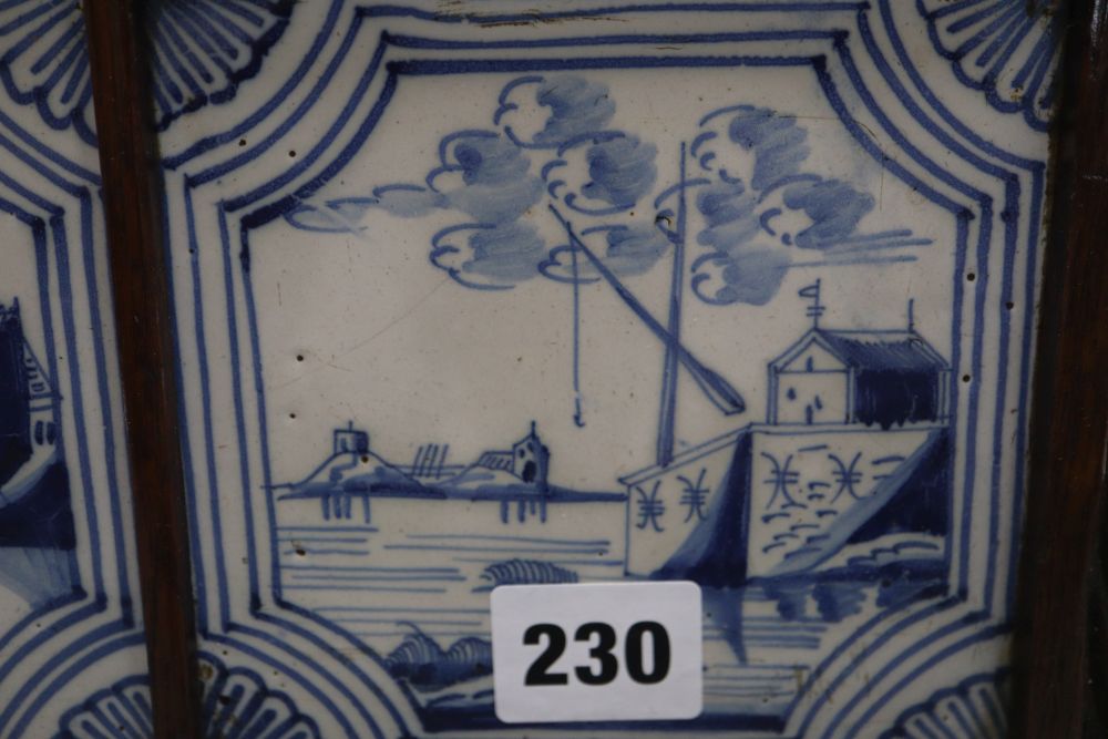 Four blue and white Delft tiles, housed in a carved oak frame, overall 35cm sq.